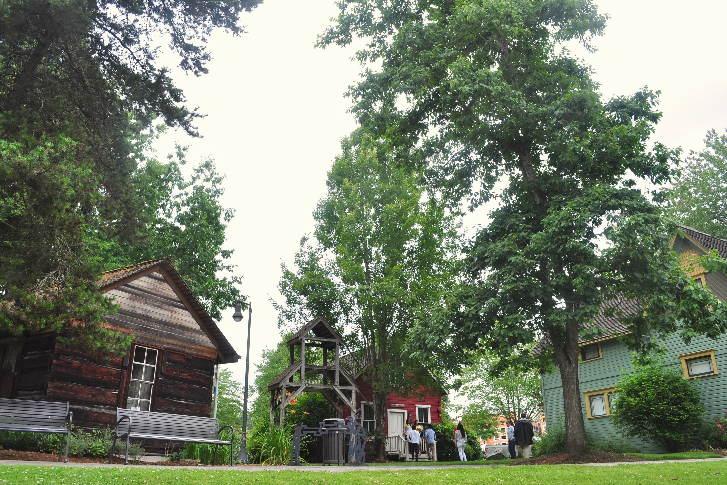 Historic wooden buildings under tall trees at Bothell Landing park